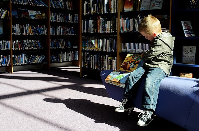 Imagen de un niño pequeño leyendo en una biblioteca